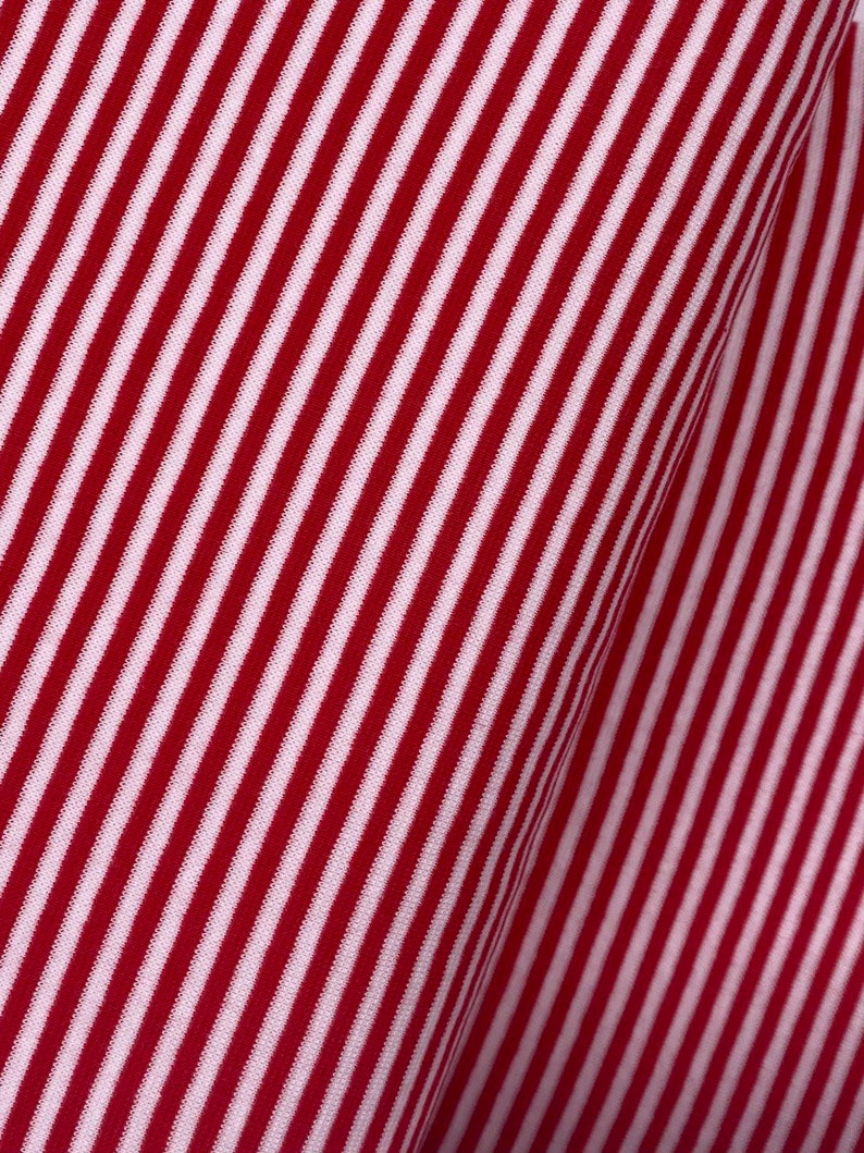 May include: Red and white striped fabric with a diagonal pattern. The fabric is folded over, creating a crease.