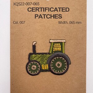 Op de afbeelding: Groene tractor geborduurde patch met gele details. De patch is 1,65 cm breed en is gemaakt van 50% polyester en 50% rayon. De patch is gelabeld "Certificated Patches" en "Quality Trimmings".