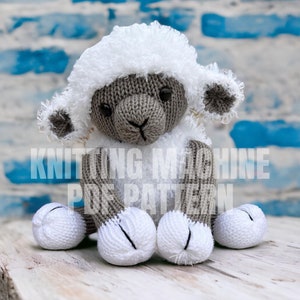 May include: A knitted gray and white sheep toy with a fluffy white fleece. The sheep is sitting on a light wood surface.