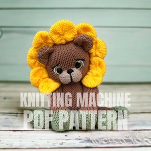 May include: Knitting machine PDF pattern for a brown lion with a yellow sunflower mane. The lion is sitting on a white wooden surface.