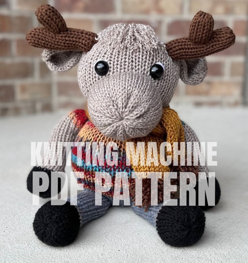 May include: Knitting machine PDF pattern for a gray knitted moose wearing a plaid scarf. The moose has brown antlers and black eyes.
