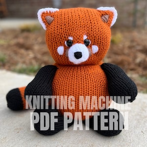 May include: Knitting machine PDF pattern for a red panda plush toy. The toy is orange with black arms and legs and white facial features.