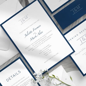 May include: Elegant wedding invitation suite featuring white cards with navy blue borders. The invitations include the initials "J&M" and event details. A matching navy blue envelope is also included.