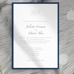 May include: A formal wedding invitation with a navy blue border. The invitation features the names "Juliette Freeman" and "Mark Alan" in elegant script. The text includes the wedding date, time, and location: The Tithe Barn, Ditcham, Hampshire.