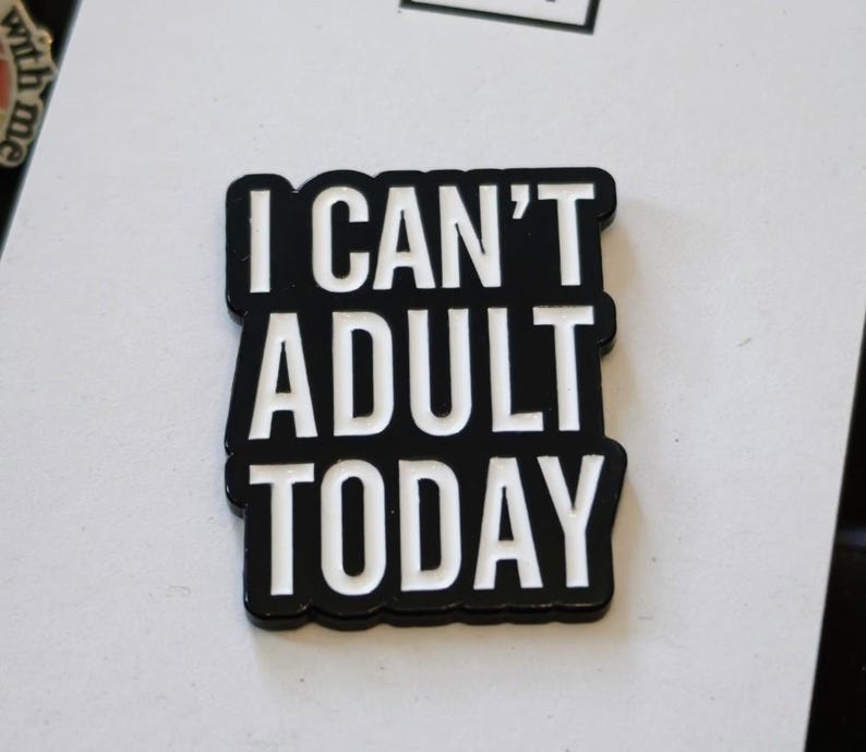 Puede incluir: Un pin de esmalte rectangular con fondo negro y letras blancas en negrita que dicen I CAN'T ADULT TODAY. El texto est&aacute; dispuesto en tres l&iacute;neas apiladas con un estilo de fuente sans-serif y un acabado suave y brillante en toda la pieza.
