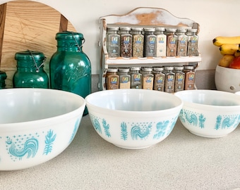 May include: Four white mixing bowls with a blue and white rooster design. The bowls are arranged in a row from largest to smallest.