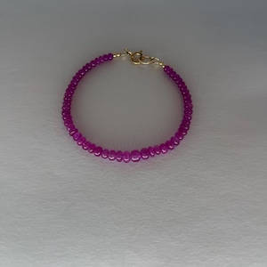 May include: A purple beaded bracelet with a gold clasp.