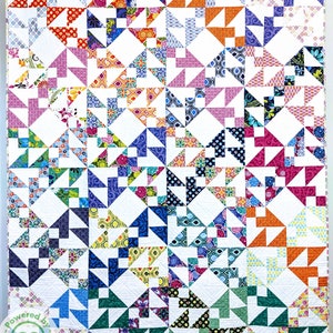 May include: A colourful quilt with a white background and a variety of geometric patterns in shades of blue, green, pink, orange, and yellow. The quilt is made up of small squares and triangles, and it is quilted with a simple stitch. The quilt is hanging on a wall, and there is a small logo in the bottom left corner that says "Powered by SS Quilting".