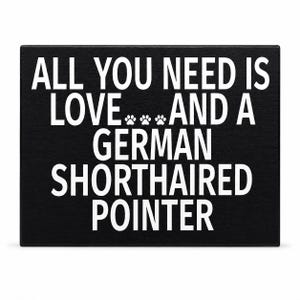 A rectangular black plaque or sign with bold white text reading 'ALL YOU NEED IS LOVE.