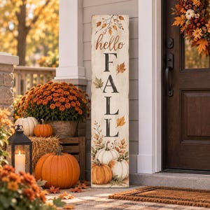 May include: A tall, rectangular wooden porch sign with a distressed white finish. The sign features the text "hello FALL" in black and brown lettering, decorated with painted autumn leaves and illustrations of white and orange pumpkins.