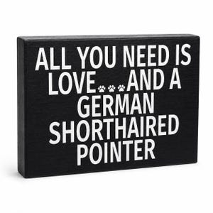 A rectangular black wooden sign with bold white text reading 'ALL YOU NEED IS LOVE.