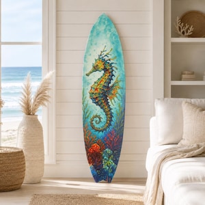 May include: A surfboard featuring a vibrant, detailed illustration of a seahorse swimming among colorful coral reefs. The artwork uses shades of blue, orange, yellow, and red, set against a light blue, watery background with bubbles.