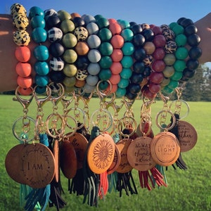 May include: A set of colorful beaded bracelets with wooden charms attached. The charms have inspirational messages such as "I am", "Let your light shine", and "Always stay humble and kind".