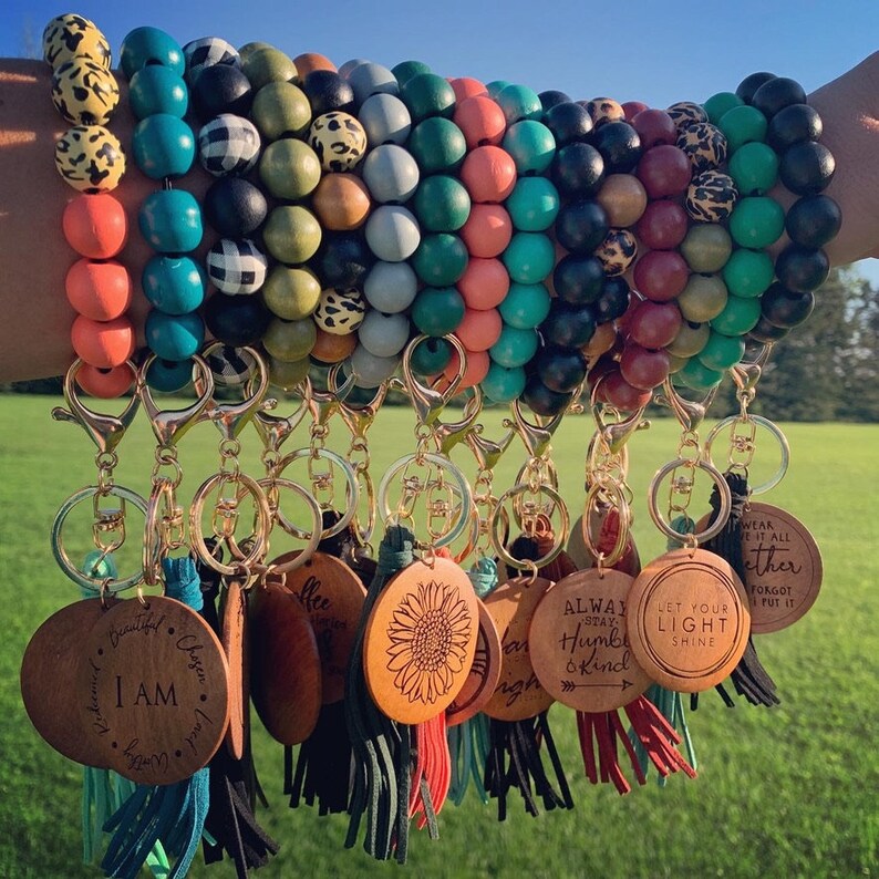 May include: A set of colorful beaded bracelets with wooden charms attached. The charms have inspirational messages such as "I am", "Let your light shine", and "Always stay humble and kind".