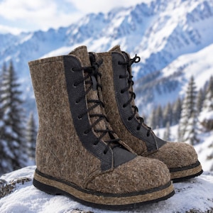 May include: A pair of brown felt winter boots with black leather accents and black laces. The boots are set against a snowy, mountainous backdrop, suggesting cold weather and outdoor activities.