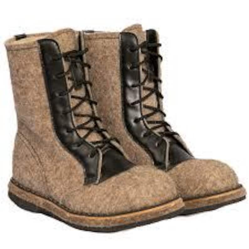 May include: A pair of brown felt boots with black leather accents and laces. The boots have a rounded toe and a sturdy sole. The boots are designed for cold weather and are approximately 10 inches tall.