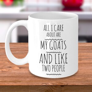 Peut inclure: Une tasse &agrave; caf&eacute; en c&eacute;ramique blanche avec du texte noir qui dit "All I care about are my goats and like two people".