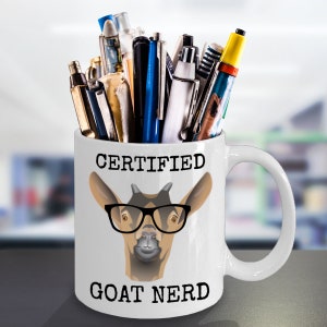 May include: White ceramic mug with a black and brown goat wearing glasses and the text "CERTIFIED GOAT NERD". The mug is filled with pens and pencils.