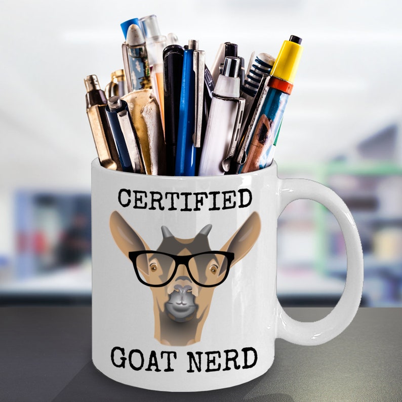 May include: White ceramic mug with a black and brown goat wearing glasses and the text "CERTIFIED GOAT NERD". The mug is filled with pens and pencils.