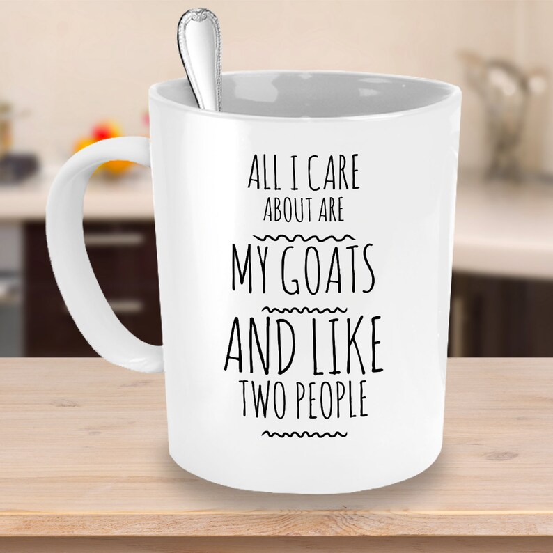 Peut inclure: Une tasse &agrave; caf&eacute; en c&eacute;ramique blanche avec un motif noir qui dit "All I care about are my goats and like two people".