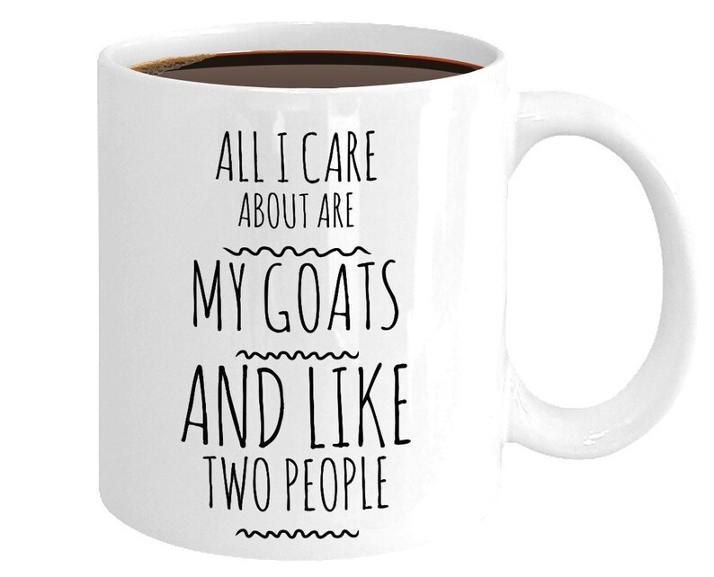 Peut inclure: Une tasse &agrave; caf&eacute; en c&eacute;ramique blanche avec du texte noir qui dit "All I care about are my goats and like two people".