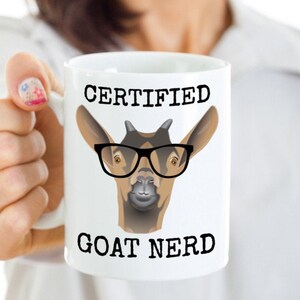 May include: White ceramic mug with a black and brown goat wearing glasses and the text "CERTIFIED GOAT NERD".