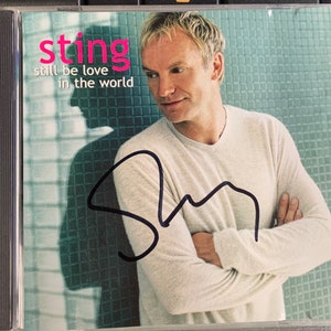 Op de afbeelding: Een CD-hoes met een foto van Sting op de voorkant. De titel van het album is "Sting: Still Be Love in the World". De CD-hoes is gesigneerd door Sting.