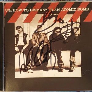 U2 “How To Dismantle An Atomic Bomb” CD 3x Hand-Signed Autograph by Bono, The Edge and Adam Clayton in Black w/ LOA