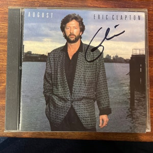 Okładka płyty CD Erica Claptona „August” z autografem Erica Claptona wykonanym czarnym tuszem z LOA