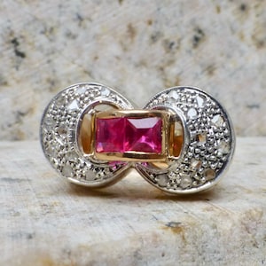 May include: A gold and silver ring with a pink square gemstone surrounded by smaller white gemstones.