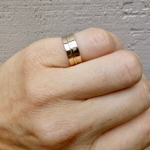May include: A gold band ring with a double groove design.