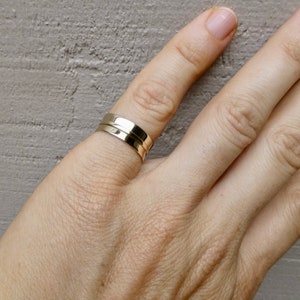 May include: A gold ring with a simple, modern design. The ring is made of two bands that are stacked on top of each other.