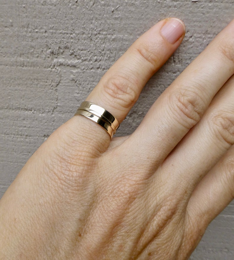 May include: A gold ring with a simple, modern design. The ring is made of two bands that are stacked on top of each other.