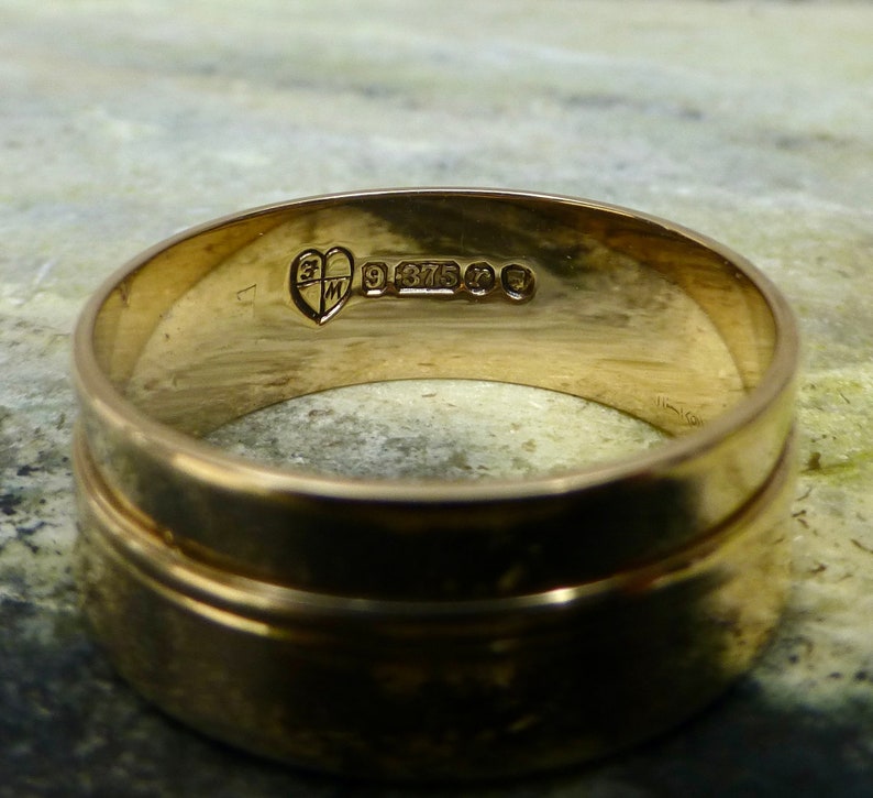 May include: A gold wedding band with a heart-shaped hallmark and the inscription "9 375" on the inside of the band.