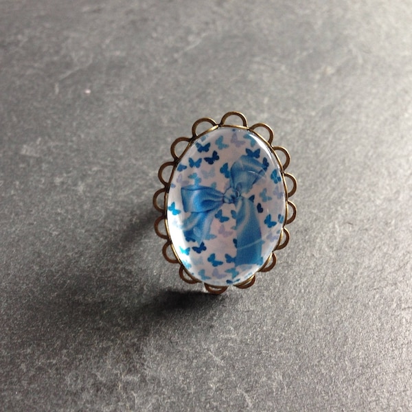 bague ovale nœud bleu sur fond papillons