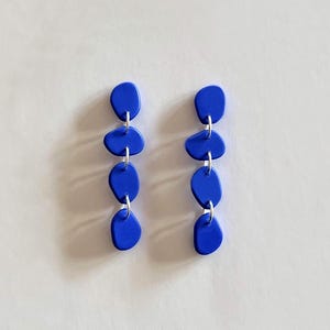 Peut inclure: Une paire de boucles d'oreilles pendantes bleues avec quatre perles en forme de goutte sur chaque boucle d'oreille.