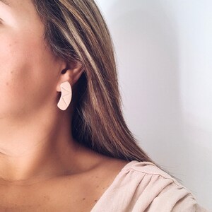 Model wearing modern minimalist beige stud earrings for size reference handmade from polymer clay by Vertseas.