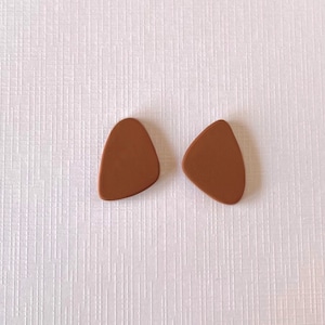 Può includere: Un paio di orecchini marroni a forma di triangolo.