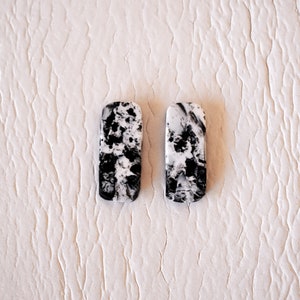 Könnte beinhalten: Ein Paar rechteckige Ohrringe in Schwarz und Weiß mit Marmormuster.
