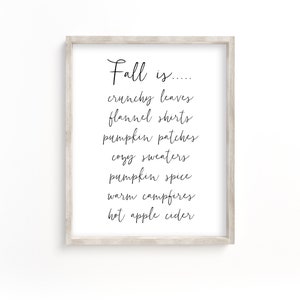 May include: A framed print with the text "Fall is..." followed by a list of fall-themed words: crunchy leaves, flannel shirts, pumpkin patches, cozy sweaters, pumpkin spice, warm campfires, and hot apple cider.