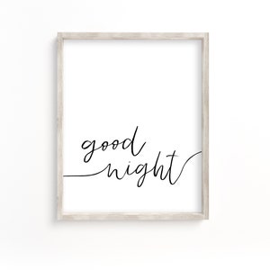 May include: A white framed print with the text "good night" written in black cursive script.