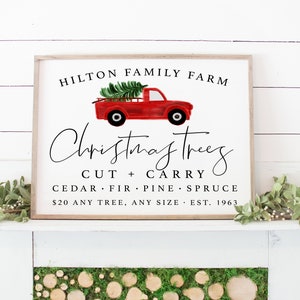May include: A white sign with a red truck carrying a Christmas tree. The sign reads "HILTON FAMILY FARM Christmas Trees CUT + CARRY CEDAR FIR PINE SPRUCE $20 ANY TREE, ANY SIZE EST. 1963".