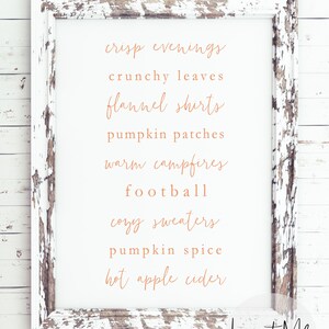 May include: A white distressed wood frame with a white background and a list of fall-themed words in a copper-colored font. The words are: crisp evenings, crunchy leaves, flannel shirts, pumpkin patches, warm campfires, football, cozy sweaters, pumpkin spice, hot apple cider. The bottom right corner of the frame has the text "Lux + Me PRINTS".