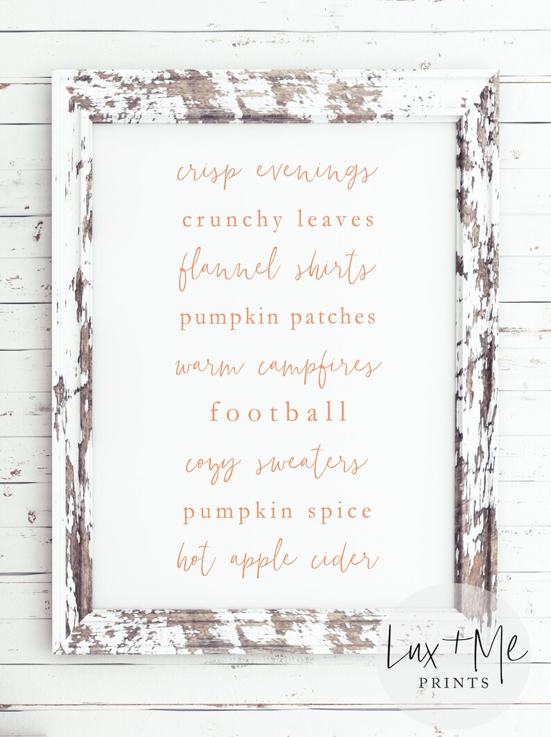 May include: A white distressed wood frame with a white background and a list of fall-themed words in a copper-colored font. The words are: crisp evenings, crunchy leaves, flannel shirts, pumpkin patches, warm campfires, football, cozy sweaters, pumpkin spice, hot apple cider. The bottom right corner of the frame has the text "Lux + Me PRINTS".