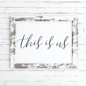 Pu&ograve; includere: Cornice in legno bianco invecchiato con il testo "this is us" in scrittura corsiva nera.