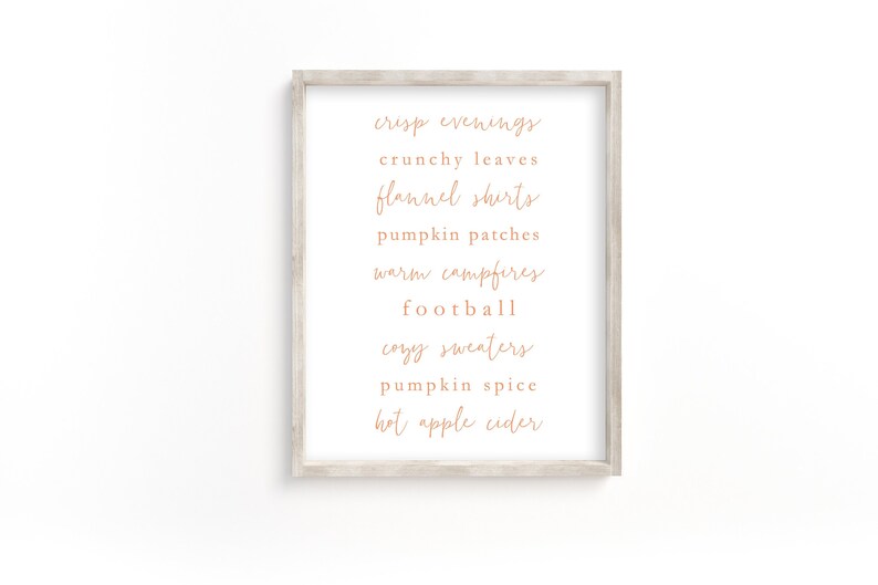 May include: A framed print with a list of fall-themed words in a handwritten font, including "crisp evenings", "crunchy leaves", "flannel shirts", "pumpkin patches", "warm campfires", "football", "cozy sweaters", "pumpkin spice", and "hot apple cider".