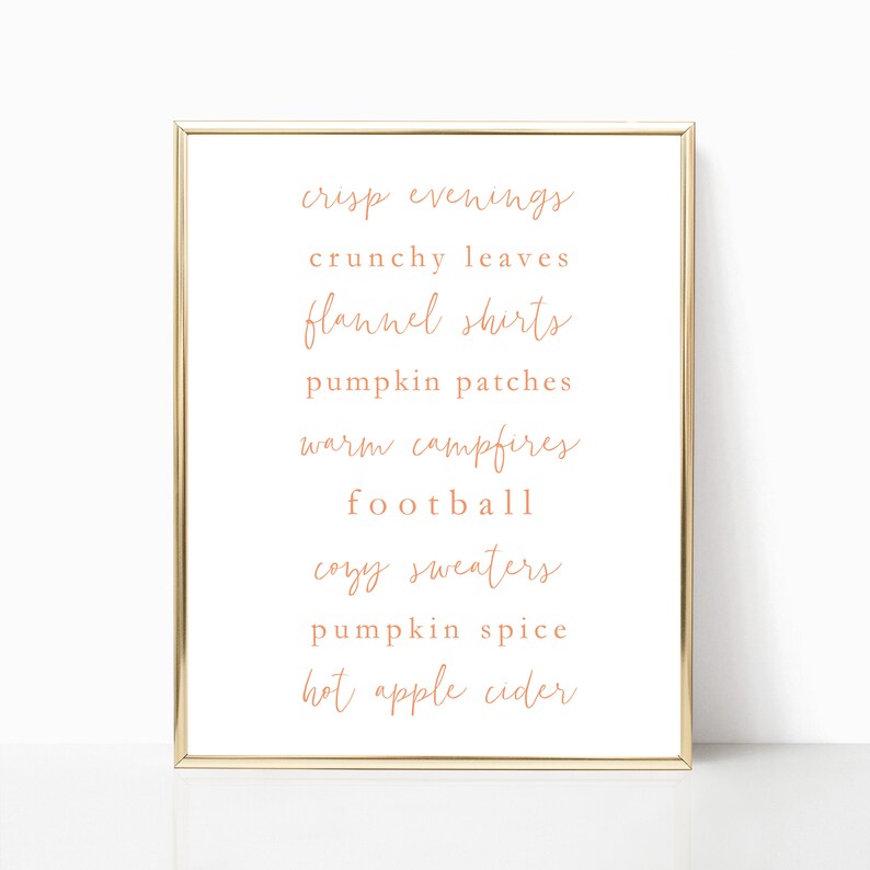 May include: A printable wall art design with a gold frame and a white background. The text reads: "crisp evenings, crunchy leaves, flannel shirts, pumpkin patches, warm campfires, football, cozy sweaters, pumpkin spice, hot apple cider".