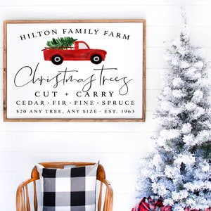 May include: A white sign with brown wood framing, advertising Christmas trees for sale at Hilton Family Farm. The sign features a red pickup truck with a Christmas tree in the bed. The text reads: "Hilton Family Farm, Christmas Trees, Cut + Carry, Cedar, Fir, Pine, Spruce, $20 Any Tree, Any Size, Est. 1963."
