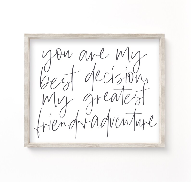 May include: A framed print with a white background and black calligraphy text that reads "you are my best decision, my greatest friend + adventure".