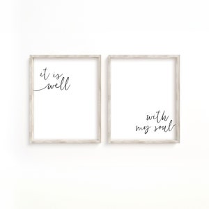 May include: Two framed prints with white backgrounds and black calligraphy. The left print says "it is well" and the right print says "with my soul".